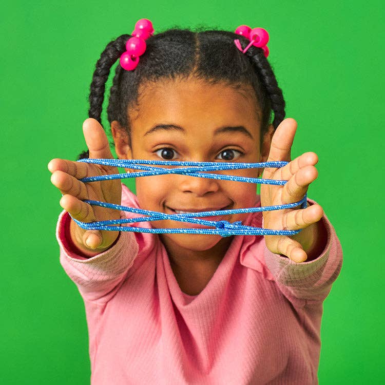 Young girl playing with Mellow Monkey Cat's Cradle blue cotton string game against a bright green background