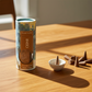 Mellow Monkey cedar scented incense cones in a decorative tube with a small white ceramic holder on a wooden table