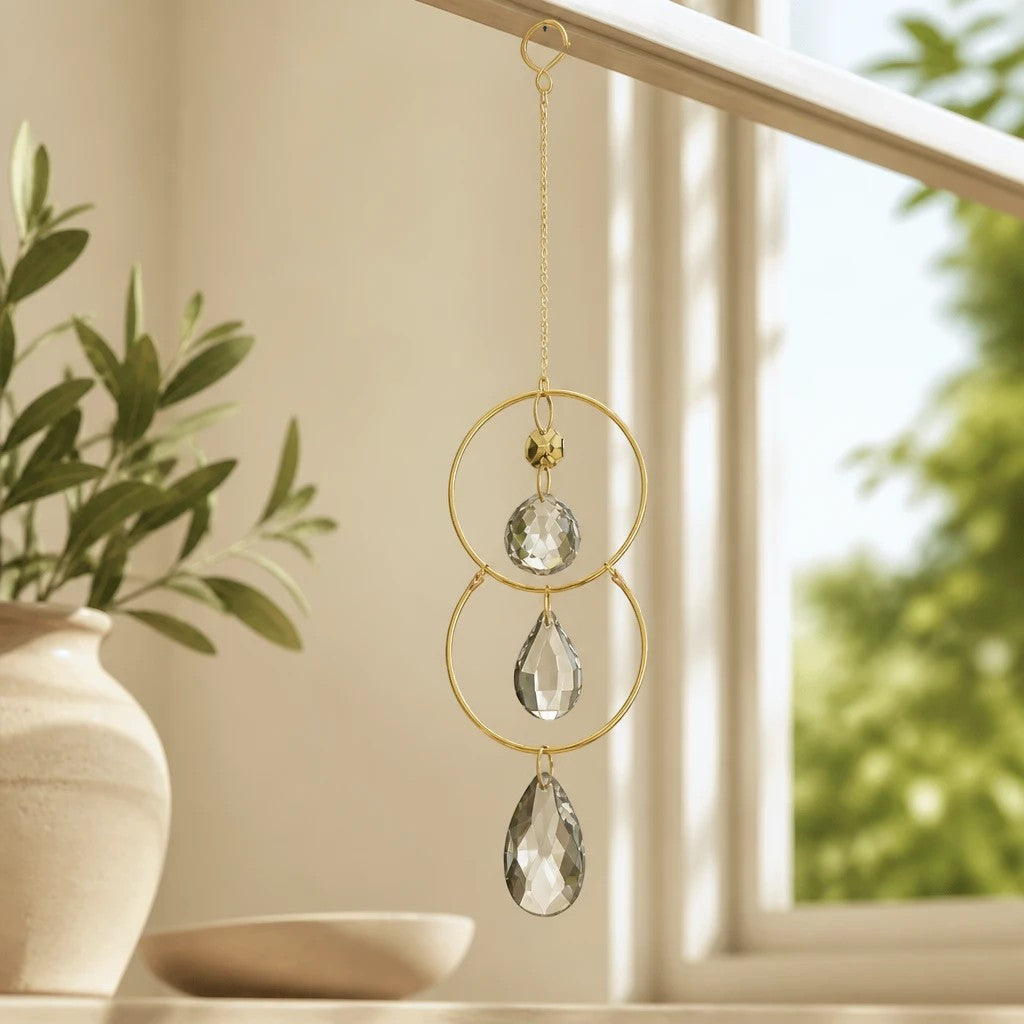 Mellow Monkey celestial suncatcher with gold rings, metallic chains, and hanging clear crystals in a bright window.