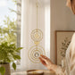 Mellow Monkey celestial suncatcher with gold rings, sun motif, and hanging crystal prism in a sunlit room.