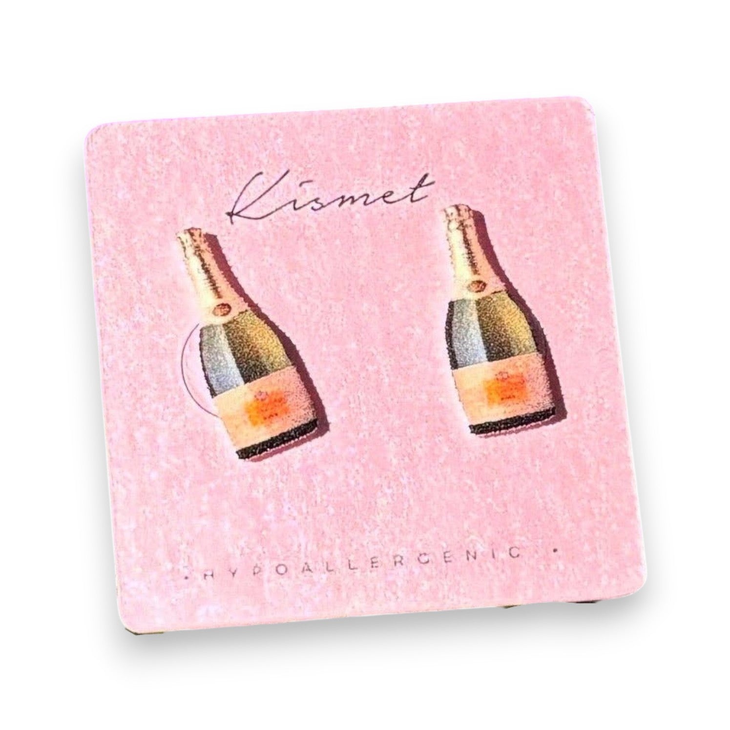 Mellow Monkey handmade champagne bottle stud earrings on a pink display card against a vibrant purple flower background.