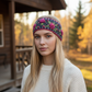 Mellow Monkey charcoal hand-knit wool headband featuring pink floral embroidery and checkerboard patterns on a model.
