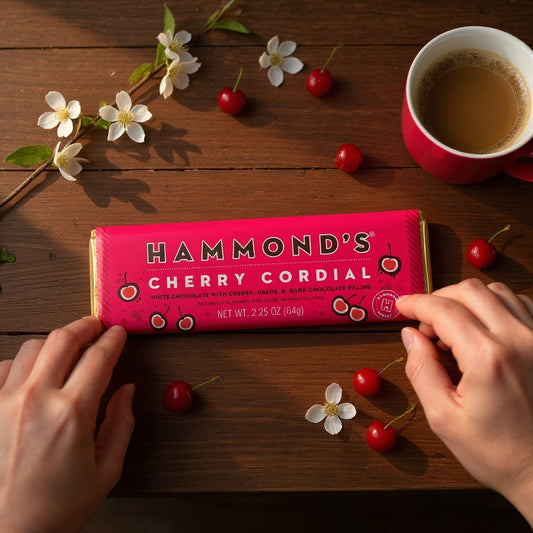 Mellow Monkey Hammond's Cherry Cordial chocolate bar with white and dark chocolate, cherries, and flowers on a table.