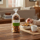 Mellow Monkey milk chocolate almond caramel popcorn in a clear bag next to a bowl of popcorn and a cup of coffee.