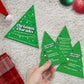 Mellow Monkey Christmas Charades game featuring tree-shaped cards with festive categories on a white rug background.