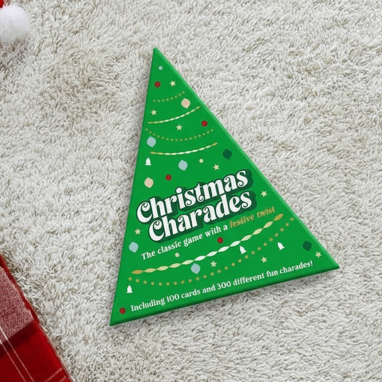 Mellow Monkey Christmas Charades game in a green tree-shaped box on a white rug with festive decorations.