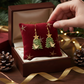 Mellow Monkey handmade Christmas tree earrings with partridge and star, featuring surgical steel wires on red velvet.