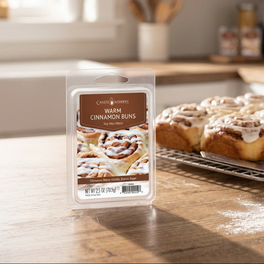 Mellow Monkey Warm Cinnamon Buns soy wax melt package on a kitchen counter next to fresh baked cinnamon rolls.