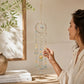 Mellow Monkey Circle of Life suncatcher with crystals, healing stones, and gold celestial charms held by a woman.