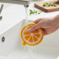 Mellow Monkey citrus slice shaped dish scrubber being rinsed under a kitchen faucet