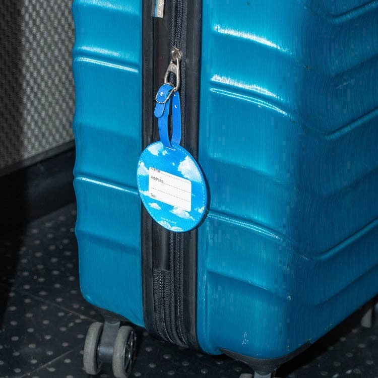 Mellow Monkey round blue cloud-patterned PU luggage tag attached to a matching blue suitcase handle