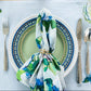 Mellow Monkey coastal hydrangea print cotton dinner napkin with a gold dragonfly napkin ring on a place setting.