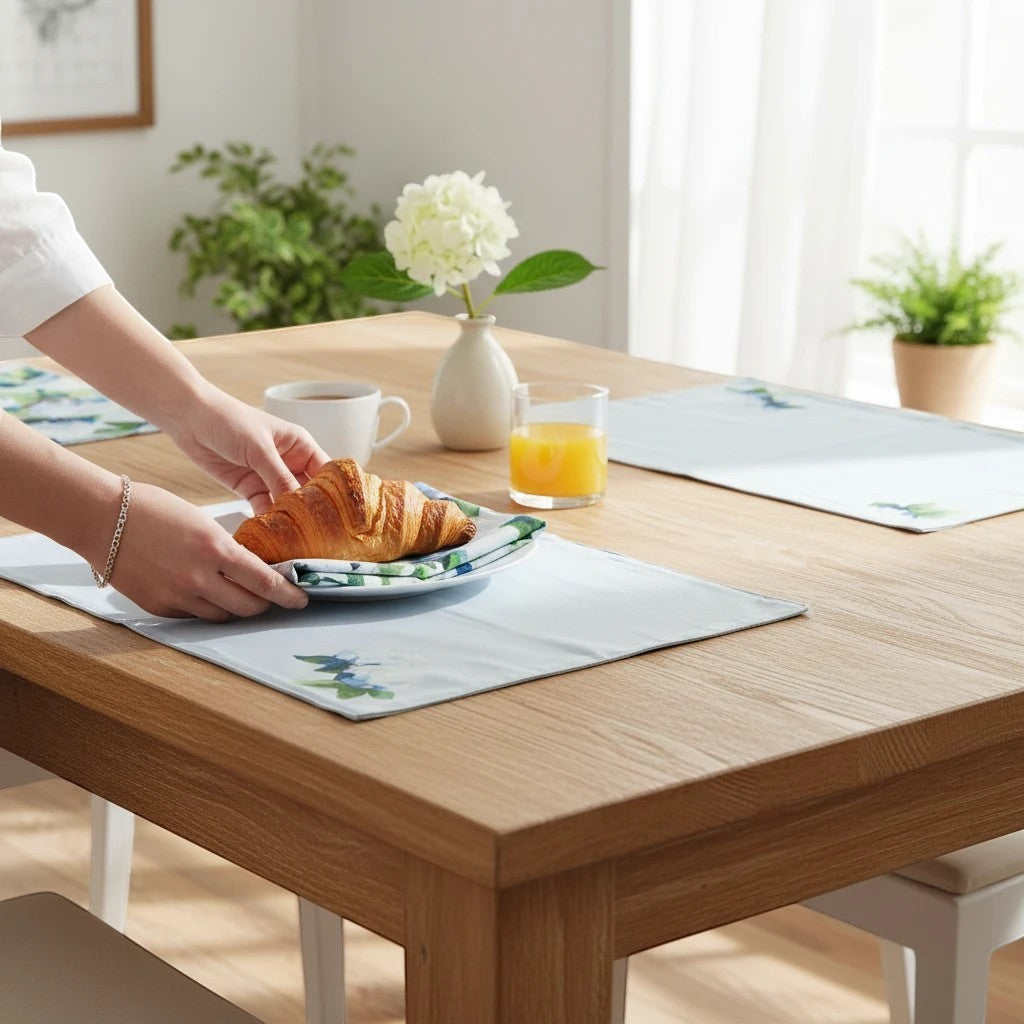 Mellow Monkey Coastal Hydrangea reversible cotton placemats on a wooden dining table with a croissant plate