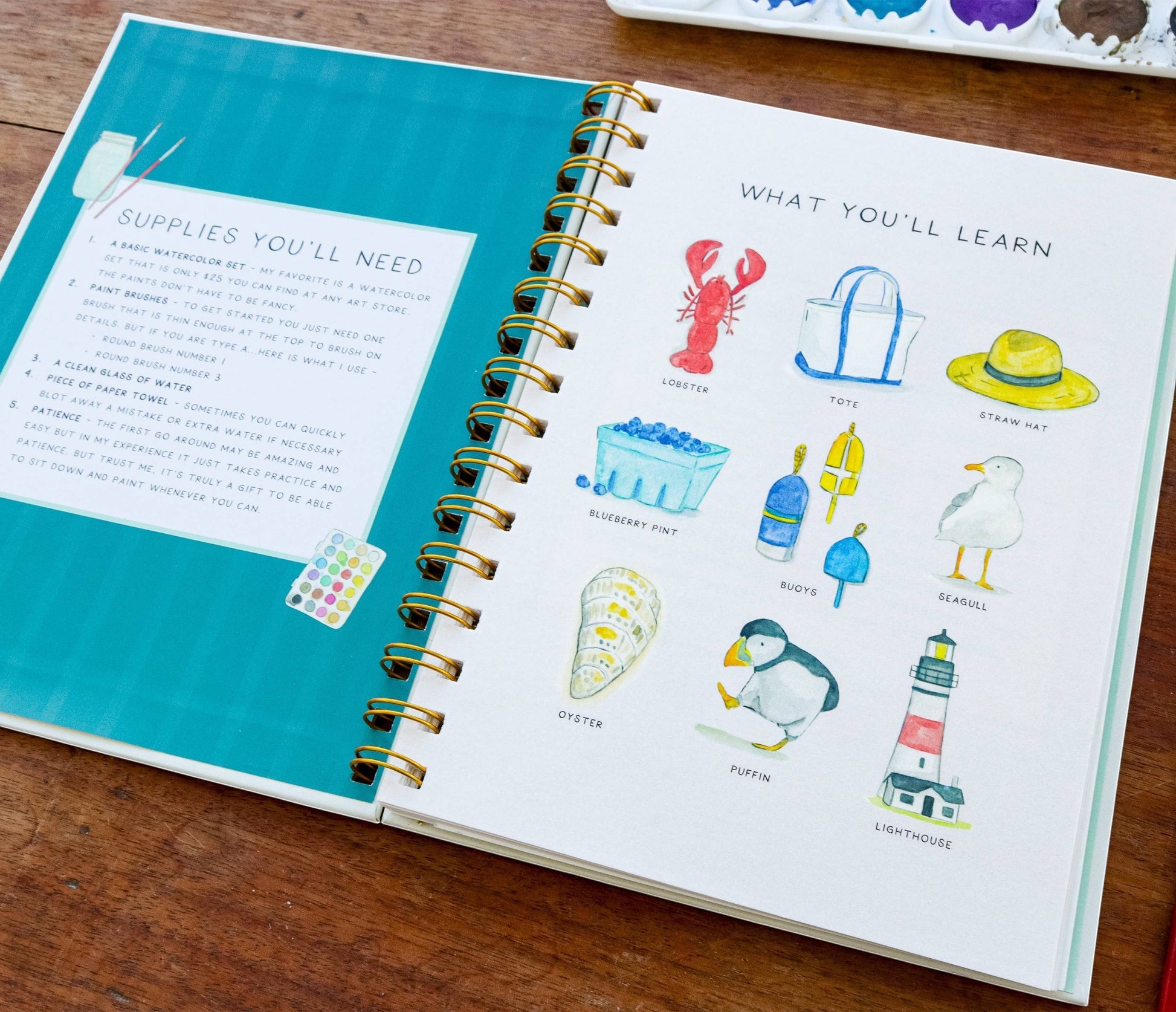 Mellow Monkey Coastin’ watercolor workbook showing supplies and paintings of lobster, tote, straw hat, blueberry pint, buoys, seagull, oyster, puffin, and lighthouse.