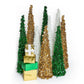 Mellow Monkey collapsible tinsel Christmas trees in gold, green, and white with stacked festive gift boxes