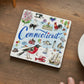 Mellow Monkey square ceramic Connecticut state coaster featuring colorful hand-drawn illustrations on a wooden table.