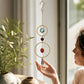 Mellow Monkey coral and crystal suncatcher ornament with bronze rings hanging in a sunlit room