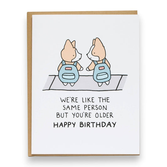 Mellow Monkey birthday card featuring two cute corgis in blue backpacks with the text We're like the same person but you're older happy birthday.