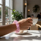 Mellow Monkey Cotton Candy Sparkle Feelzies sensory bracelet in pink glitter worn on a wrist holding a tea cup.