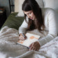 Mellow Monkey Cozy Cottage FlowArt Dot by Letter pad being used by a woman relaxing on a cozy bed with a soft blanket.