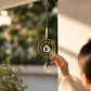 Mellow Monkey crescent moon suncatcher with bronze wire, gold chains, and a hanging crystal prism in a sunny window.