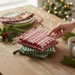 Mellow Monkey holiday crocheted pot holders in red and green with leather hanging loops on a wooden table