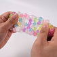 Mellow Monkey Crunch & Squish candy-themed stress ball being stretched to show colorful crunchy beads inside