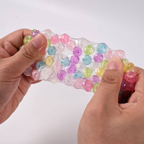 Mellow Monkey Crunch & Squish candy-themed stress ball being stretched to show colorful crunchy beads inside