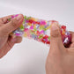 Mellow Monkey Crunch & Squish candy-themed sensory fidget toy being stretched to show colorful crunchy beads inside