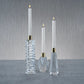 Mellow Monkey set of three clear crystal candle holders with gold accents and white taper candles on a grey surface.