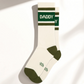 Mellow Monkey white crew socks with green stripes and the word DADDY in a retro athletic font on the cuff