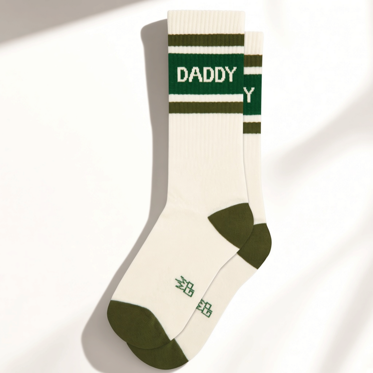 Mellow Monkey white crew socks with green stripes and the word DADDY in a retro athletic font on the cuff