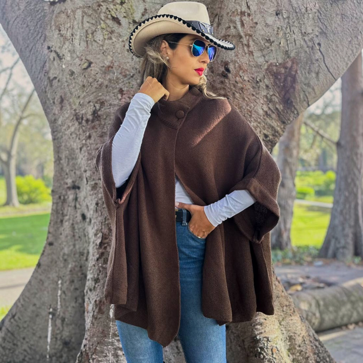 Mellow Monkey dark brown knit cape cardigan with a button neck closure worn over a white long-sleeve top and jeans.