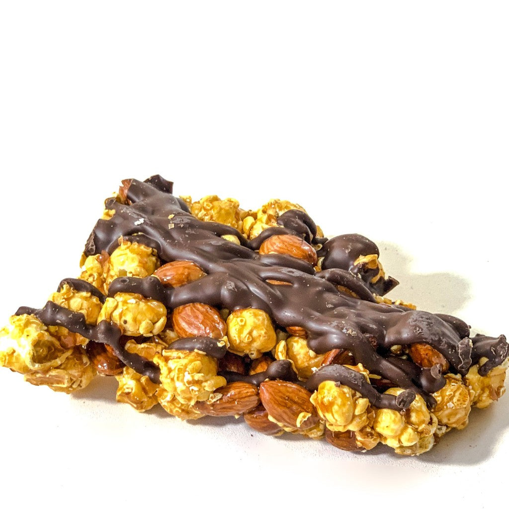 Mellow Monkey dark chocolate almond caramel popcorn cluster drizzled with rich chocolate on a white background