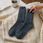 Mellow Monkey denim blue Ragg Metro crew socks with a ribbed texture resting on a cozy cream cable knit blanket