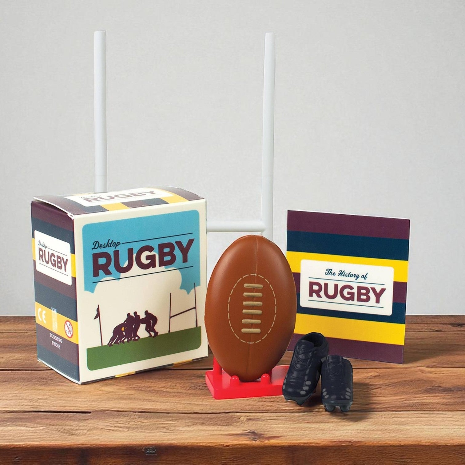 Mellow Monkey Desktop Rugby mini kit featuring a rugby ball, goal post, mini boots, and a history book on a table.