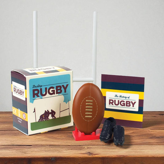 Mellow Monkey Desktop Rugby mini kit featuring a rugby ball, goal post, mini boots, and a history book on a table.