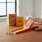 Mellow Monkey desktop Skee-Ball mini game kit with orange ramp, five metal balls, and illustrated guide on a desk.