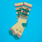 Mellow Monkey crew socks in beige with teal accents and the text I Like Dogs More Than People on a blue background.