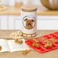 Mellow Monkey Kobe dog treat kit with a keepsake tin, red silicone bone mold, and recipe book on a wooden table.