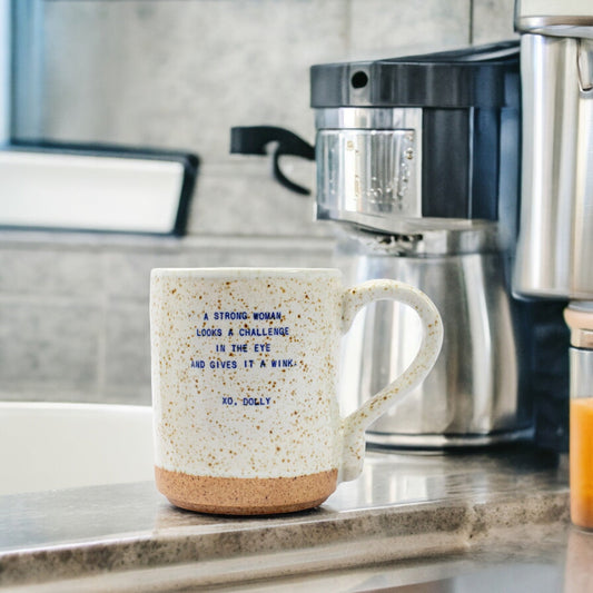 Mellow Monkey XO Dolly ceramic mug with speckled finish and inspirational Dolly Parton quote on a kitchen counter