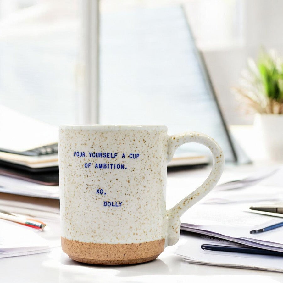 Mellow Monkey XO Dolly ceramic mug with speckled finish and Pour Yourself A Cup Of Ambition quote on a desk