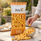 Mellow Monkey Jody's Double Cheddar popcorn in a clear bag with a bowl of cheesy popcorn on an outdoor table