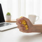 Mellow Monkey clear stress ball filled with yellow mini ducks being squeezed by a hand on a desk