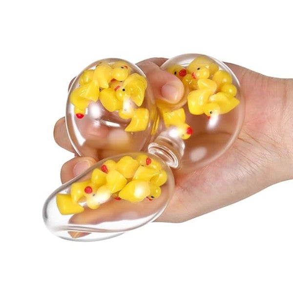 Mellow Monkey clear stress ball filled with yellow mini ducks being squeezed in a hand for sensory fidgeting.