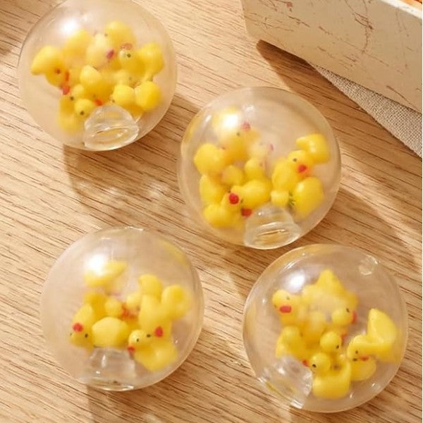 Mellow Monkey clear air-filled stress balls containing small yellow rubber ducks on a wooden surface