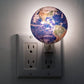 Mellow Monkey Earth night light plugged into a wall outlet, featuring a detailed globe design with soft illumination.