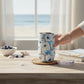 Mellow Monkey 16oz stainless steel wine tumbler with blue and white abstract Ebb and Flow pattern on a wooden table.
