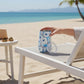 Mellow Monkey 16oz stainless steel wine tumbler with blue and white abstract pattern on a beach lounge chair.