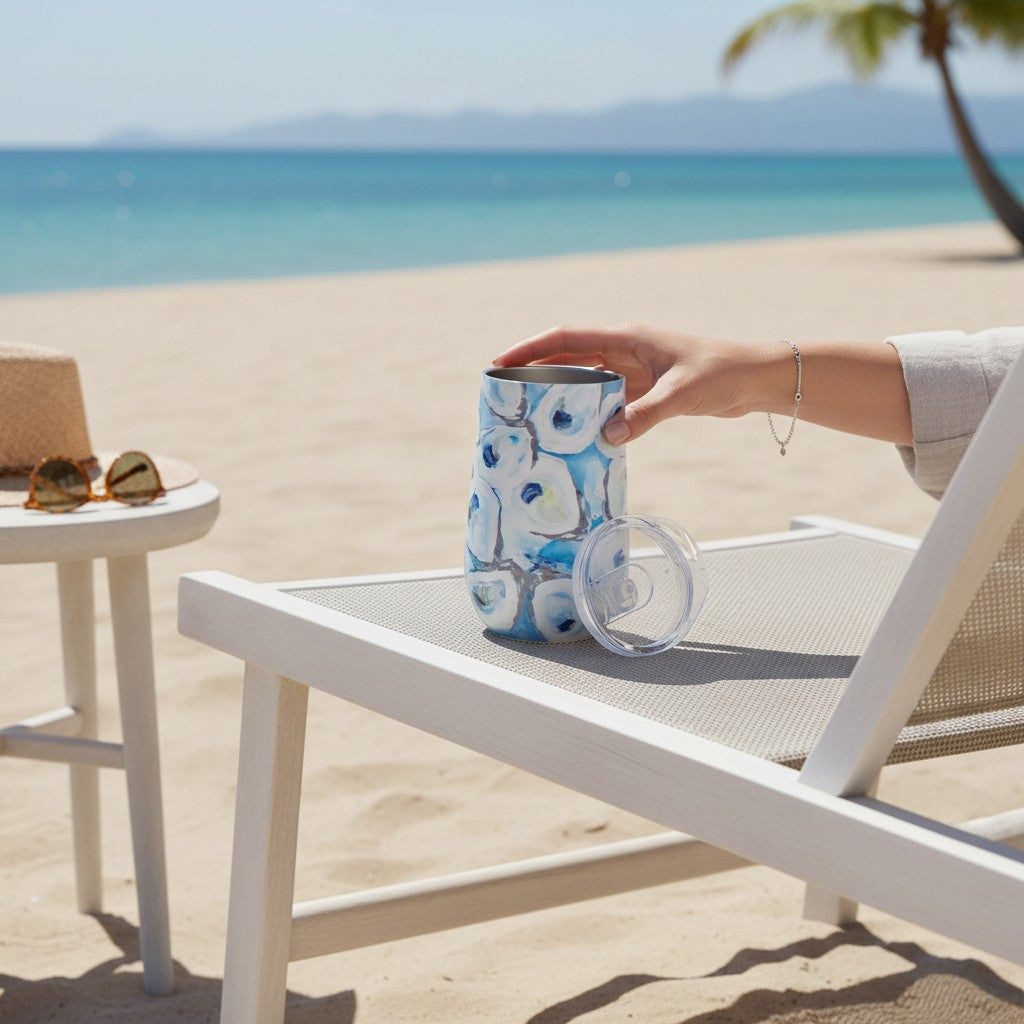 Mellow Monkey 16oz stainless steel wine tumbler with blue and white abstract pattern on a beach lounge chair.